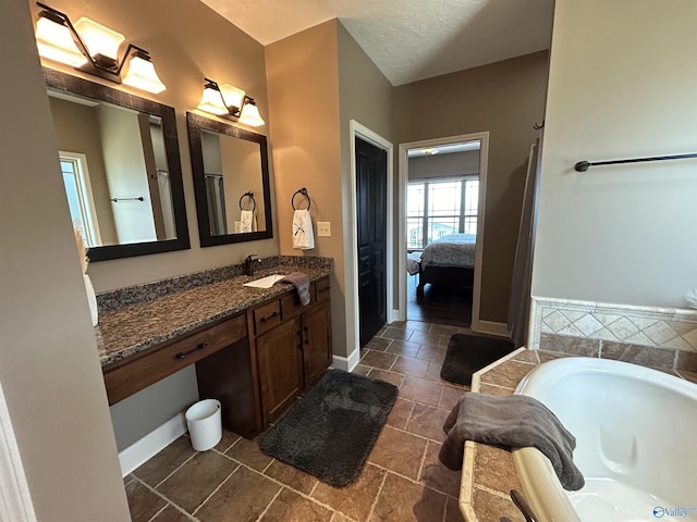 ensuite bathroom with ensuite bath, vanity, a bath, and baseboards