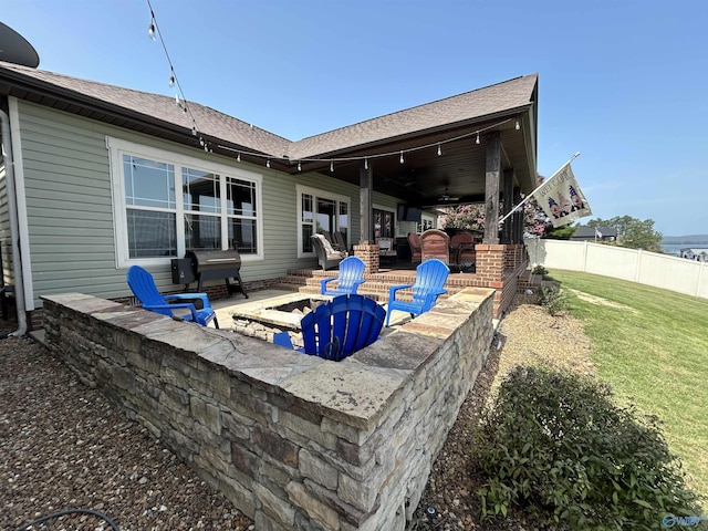 rear view of property featuring a yard, a patio, a ceiling fan, fence, and a fire pit