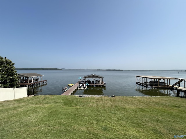 view of dock featuring a yard, a water view, and fence