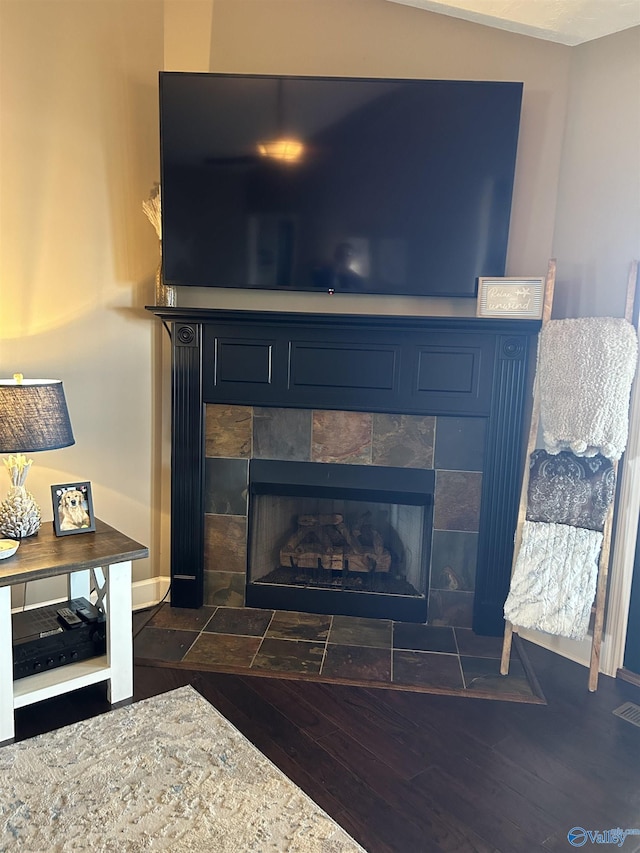 interior details with baseboards, a tiled fireplace, and wood finished floors