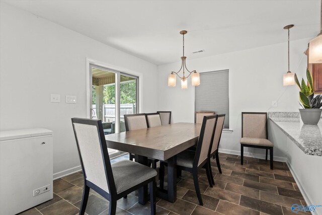 dining space featuring dark tile patterned flooring and an inviting chandelier