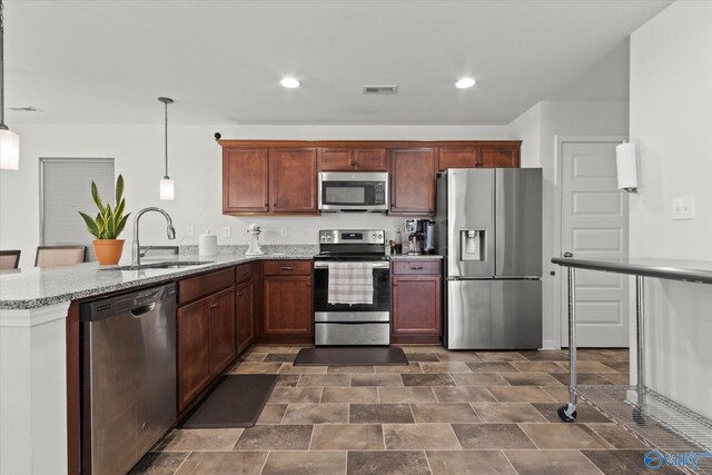 kitchen featuring dark tile patterned floors, decorative light fixtures, stainless steel appliances, sink, and kitchen peninsula