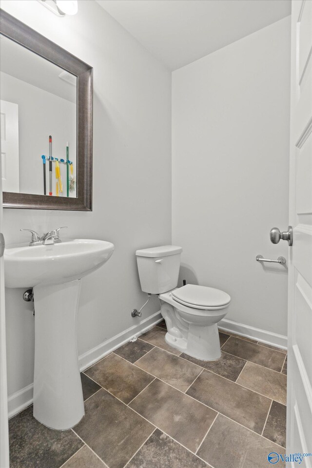 bathroom featuring toilet, sink, and tile patterned flooring