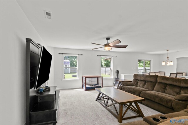 carpeted living room with ceiling fan with notable chandelier