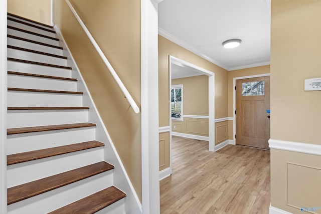 entrance foyer with crown molding and light hardwood / wood-style floors