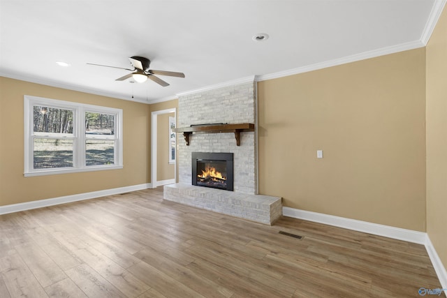 unfurnished living room featuring a brick fireplace, ornamental molding, wood-type flooring, and ceiling fan