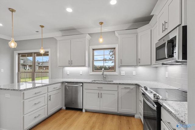 kitchen with a wealth of natural light, light hardwood / wood-style flooring, stainless steel appliances, and backsplash