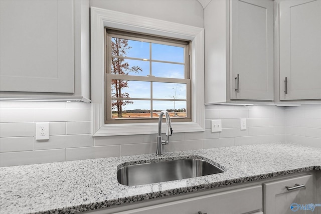 kitchen with light stone counters, tasteful backsplash, and sink