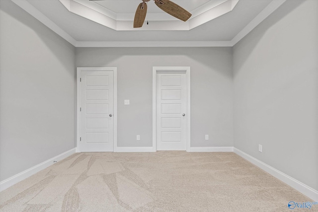 empty room featuring ornamental molding, carpet, ceiling fan, and a tray ceiling