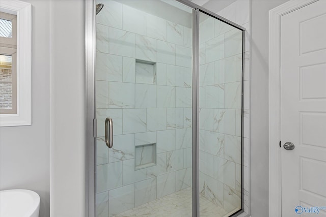 bathroom featuring a shower with shower door and toilet