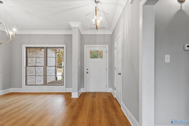 foyer entrance with crown molding, hardwood / wood-style flooring, and a notable chandelier