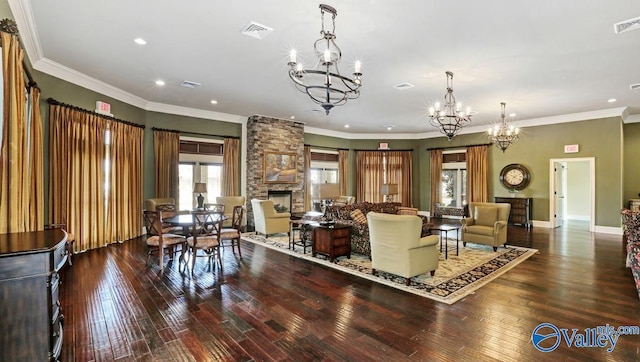 living room with a stone fireplace, crown molding, a chandelier, and hardwood / wood-style flooring