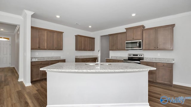 kitchen featuring appliances with stainless steel finishes, ornamental molding, dark wood-type flooring, sink, and a center island with sink