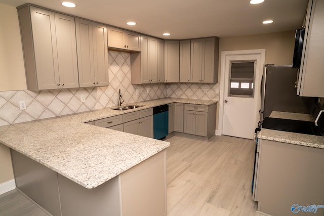 kitchen featuring sink, appliances with stainless steel finishes, a kitchen breakfast bar, kitchen peninsula, and light stone countertops