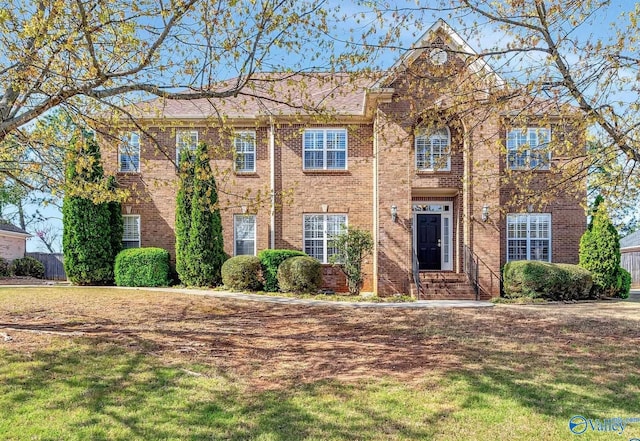 colonial house with a front lawn and brick siding