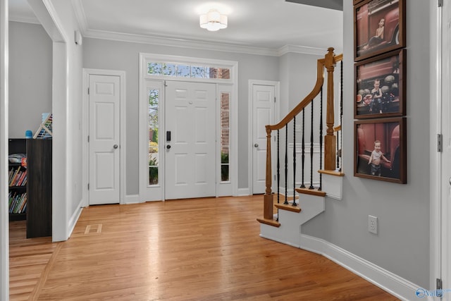 foyer featuring ornamental molding, baseboards, stairway, and light wood-style floors