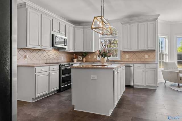 kitchen featuring a notable chandelier, light stone counters, a kitchen island, stainless steel appliances, and hanging light fixtures