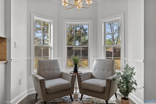 sitting room with baseboards, an inviting chandelier, ornamental molding, and wood finished floors