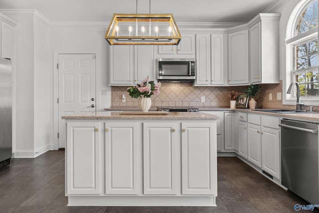 kitchen featuring tasteful backsplash, white cabinets, a sink, ornamental molding, and appliances with stainless steel finishes