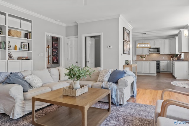 living area featuring built in shelves, light wood-style flooring, and crown molding