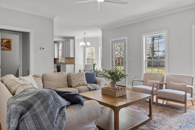 living room featuring crown molding, a wealth of natural light, and ceiling fan with notable chandelier