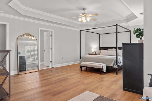bedroom featuring ornamental molding, light wood-type flooring, a raised ceiling, and baseboards