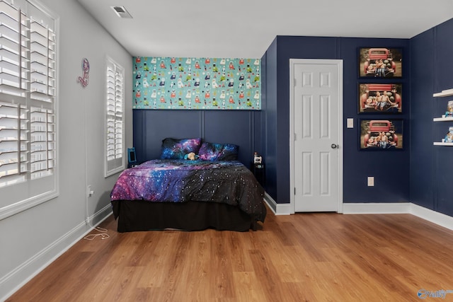 bedroom featuring wood finished floors, baseboards, and visible vents