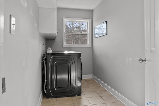 clothes washing area with light tile patterned floors and baseboards