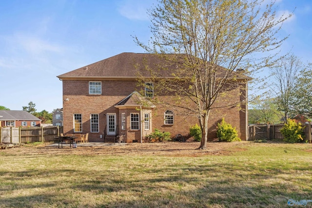 rear view of house featuring a patio, brick siding, fence, and a lawn