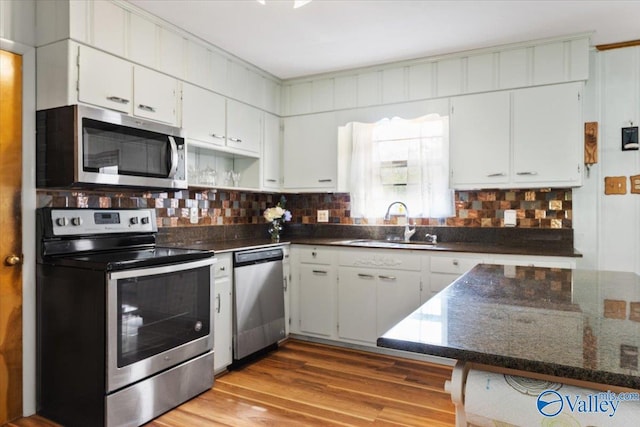 259 Old Big Cove Rd, Brownsboro, AL 35741 - kitchen featuring appliances with stainless steel finishes, a sink, white cabinets, wood finished floors, and decorative backsplash