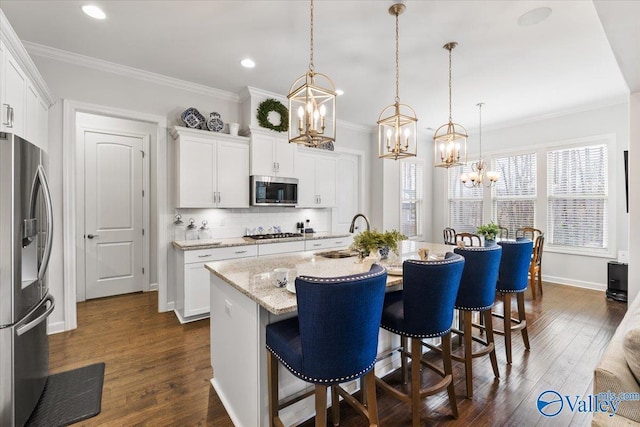 kitchen with stainless steel appliances, ornamental molding, a sink, and dark wood finished floors