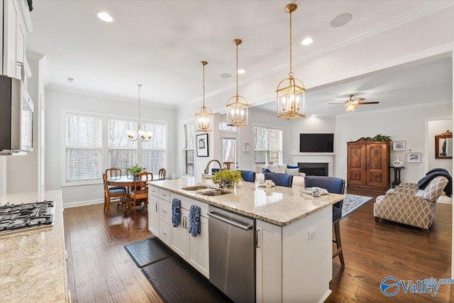 kitchen with appliances with stainless steel finishes, dark wood-type flooring, ornamental molding, white cabinets, and a sink