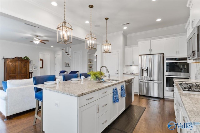 kitchen featuring dark wood finished floors, appliances with stainless steel finishes, open floor plan, white cabinetry, and a sink