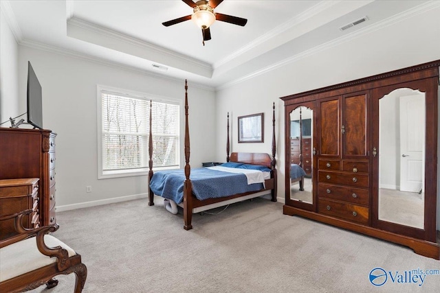 bedroom with light carpet, visible vents, a tray ceiling, and ornamental molding