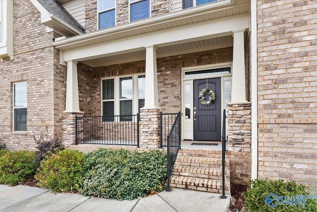 view of exterior entry with a porch and brick siding