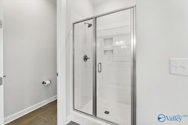 full bath featuring a stall shower, baseboards, and wood finished floors