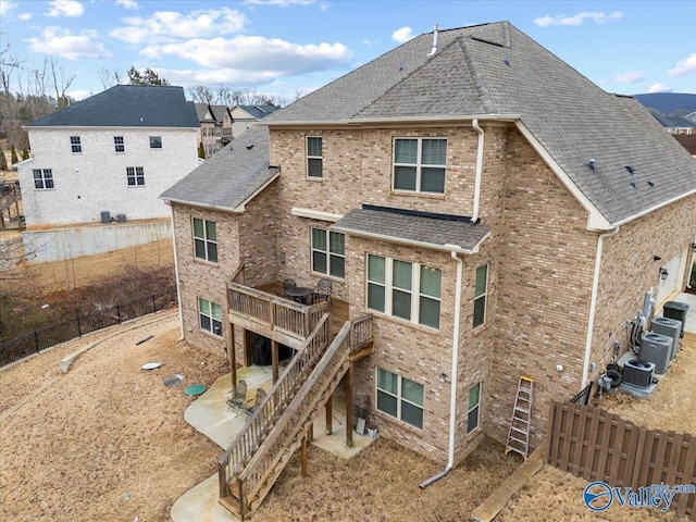 rear view of property with roof with shingles, brick siding, and stairs