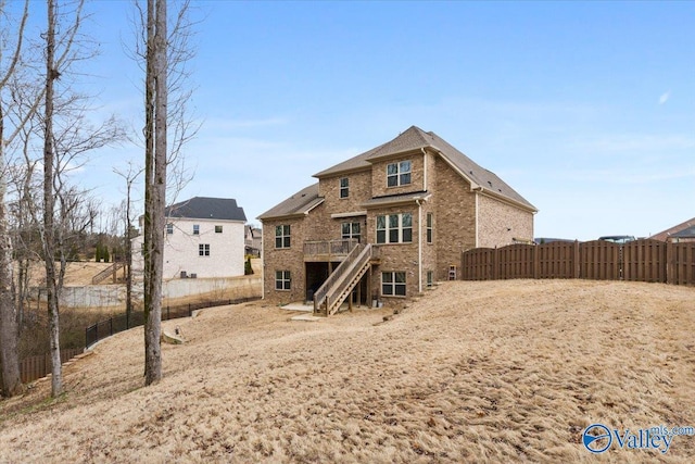 back of property featuring a wooden deck, stairs, fence, and brick siding