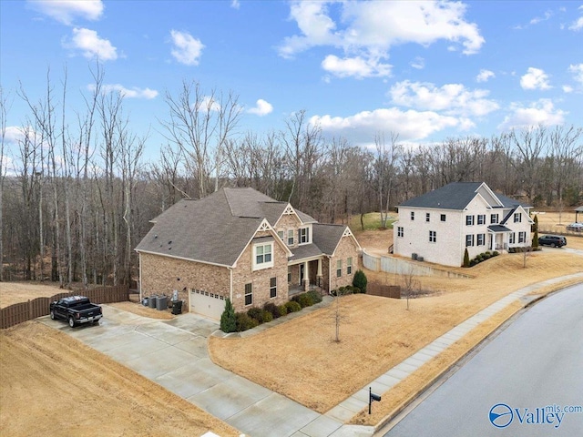 view of front facade with a garage, driveway, fence, and a view of trees