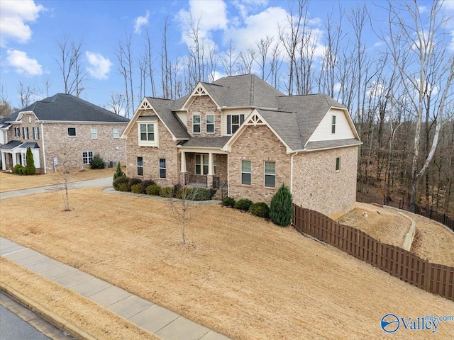 craftsman inspired home with a shingled roof, fence, and brick siding