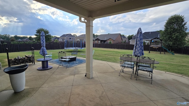 view of patio / terrace featuring a trampoline, a playground, a residential view, a fenced backyard, and a fire pit