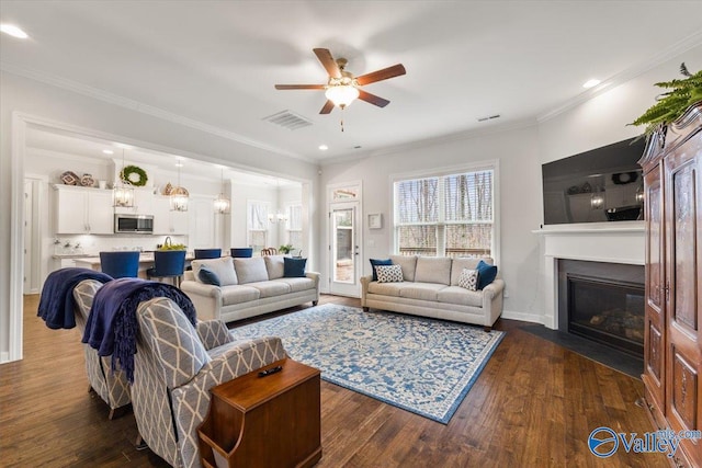 living area featuring dark wood-style floors, visible vents, and ornamental molding