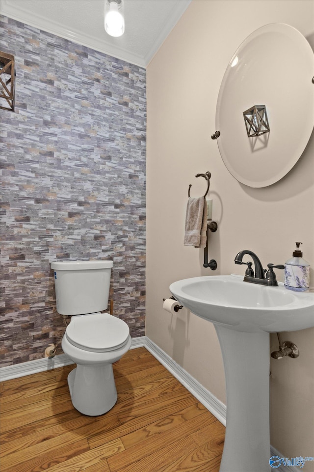 bathroom featuring a sink, ornamental molding, toilet, and wood finished floors