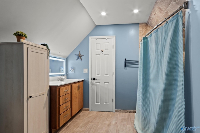 full bath with vanity, lofted ceiling, baseboards, curtained shower, and wood finished floors