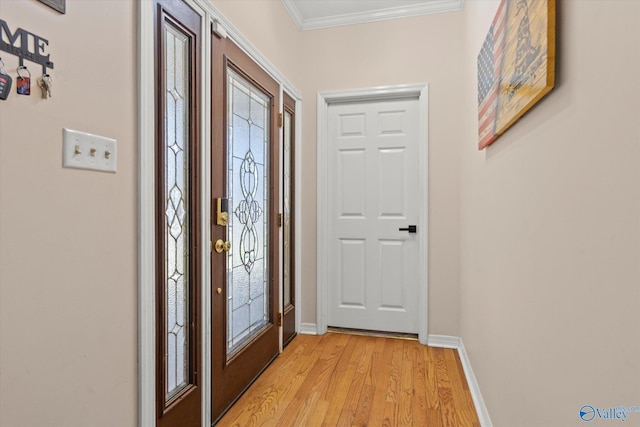 foyer entrance with crown molding, baseboards, and light wood finished floors
