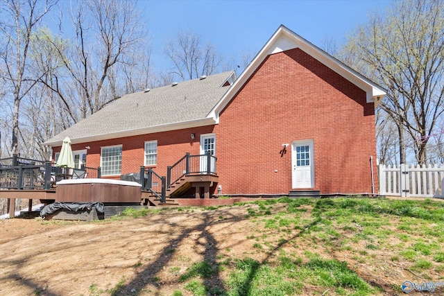 back of property with a deck, fence, and brick siding