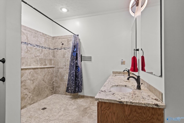 bathroom featuring double vanity, a sink, tiled shower, and crown molding