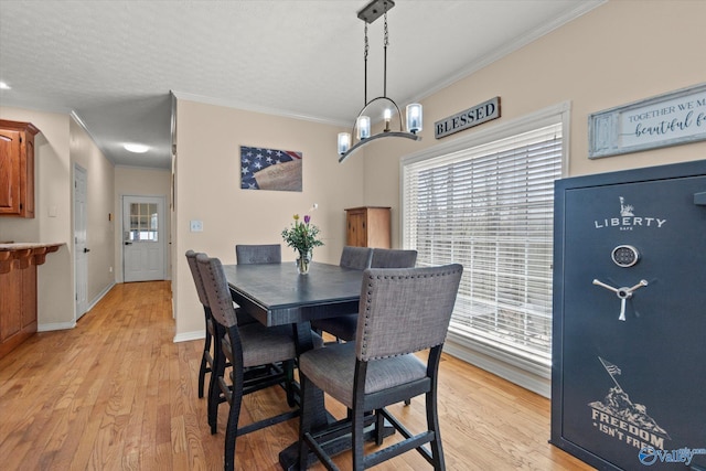 dining room featuring baseboards, crown molding, light wood-style floors, and a textured ceiling
