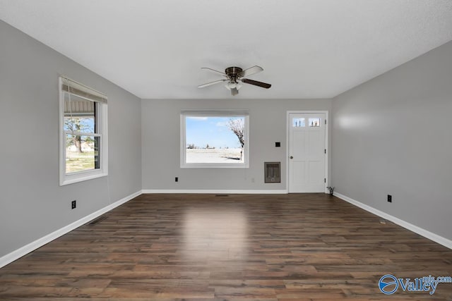 interior space with ceiling fan, dark hardwood / wood-style floors, and heating unit