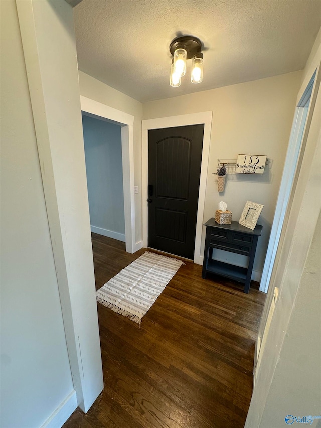 doorway to outside featuring a textured ceiling and dark hardwood / wood-style flooring